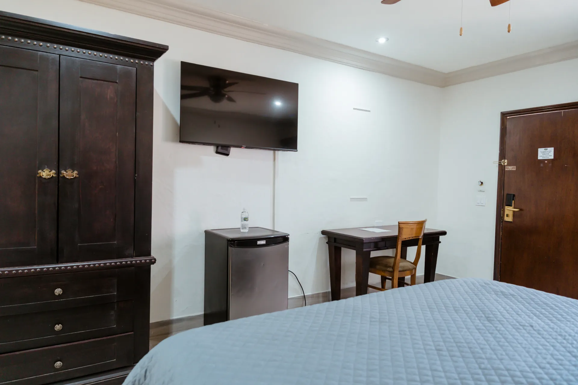 A hotel room with a bed , desk , dresser and television.