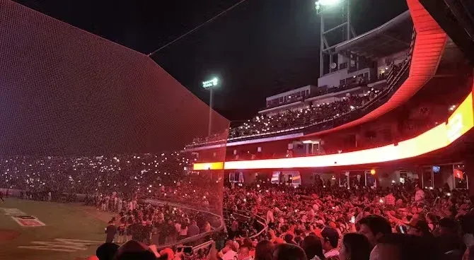 A crowd of people are watching a baseball game in a stadium at night.
