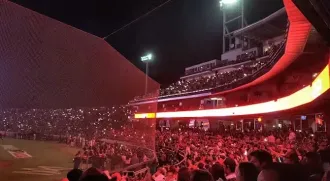 Una multitud de personas está viendo un partido de béisbol en un estadio por la noche.