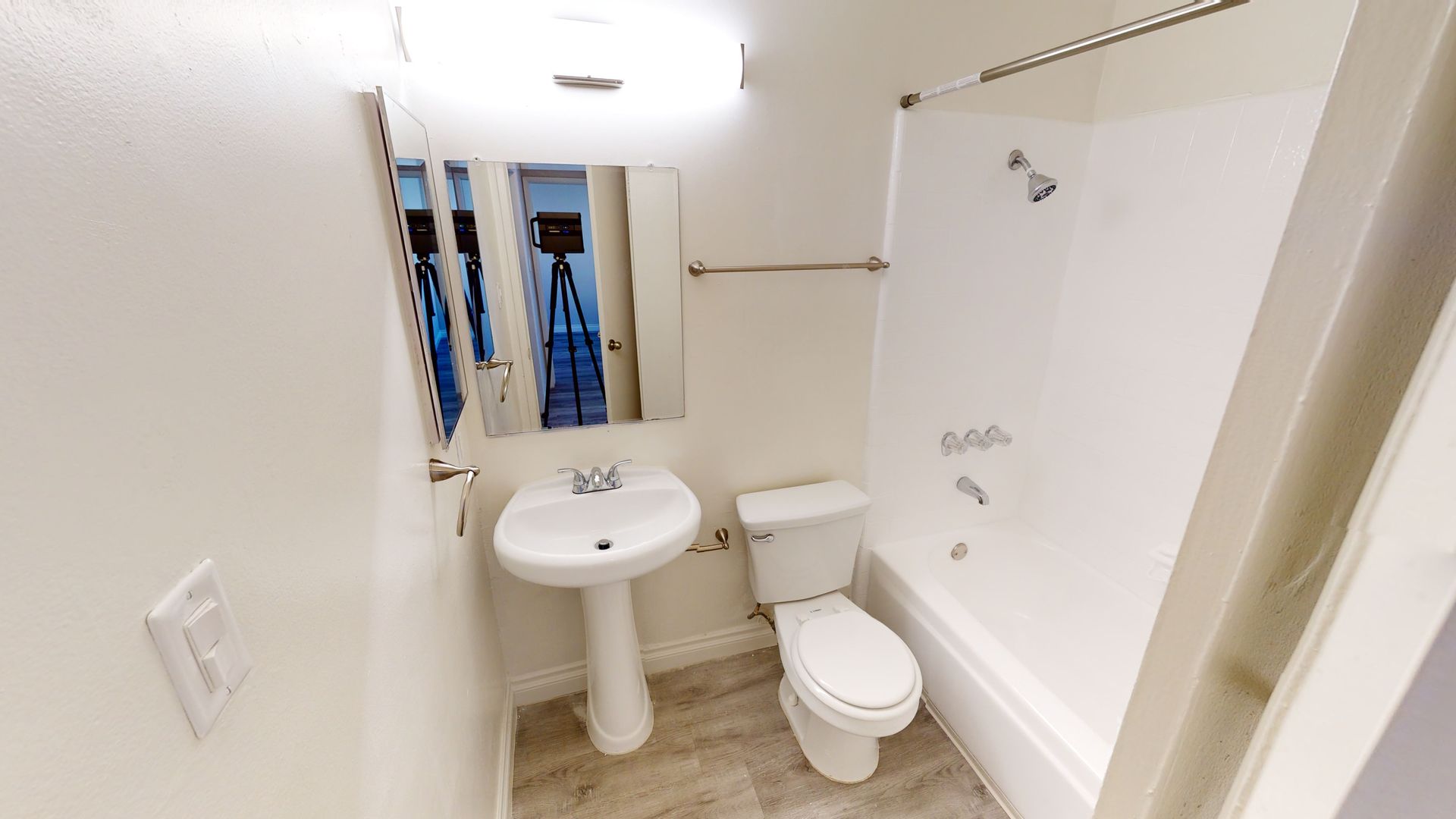 Small white bathroom with a pedestal sink, toilet, bathtub, and mirror.