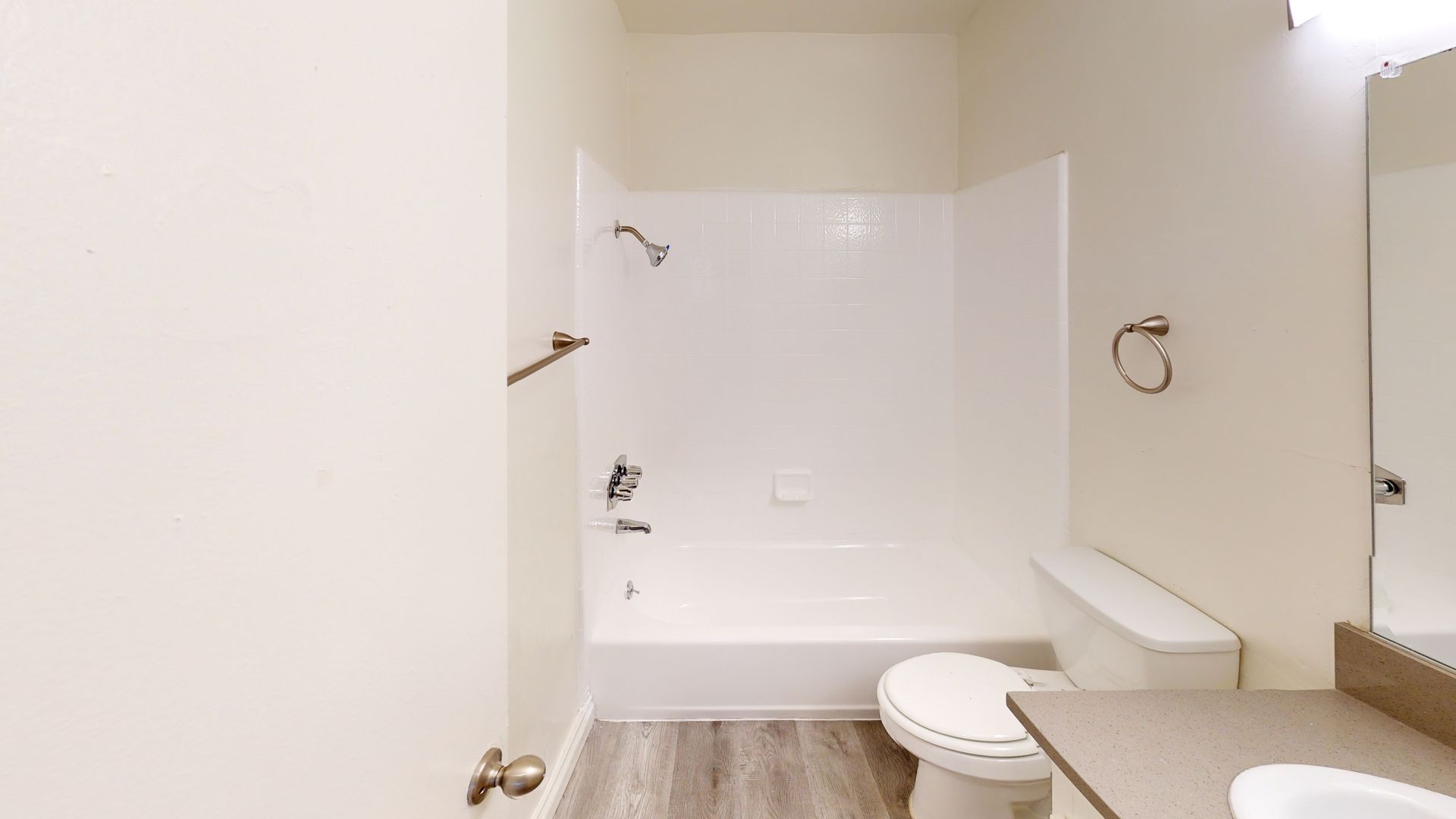 Bathroom with a white bathtub and toilet, light gray countertop, and silver fixtures.