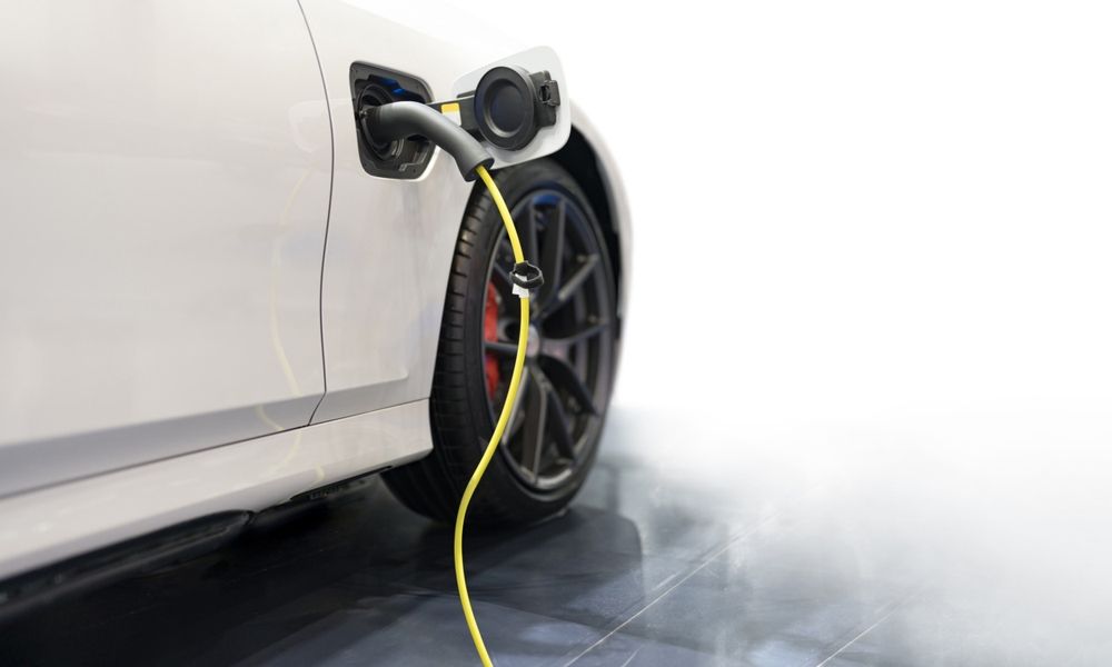 A white electric car is being charged at a charging station.