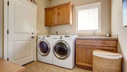 Laundry room with washer and dryer, wooden cabinets, a sink, and a closed door.