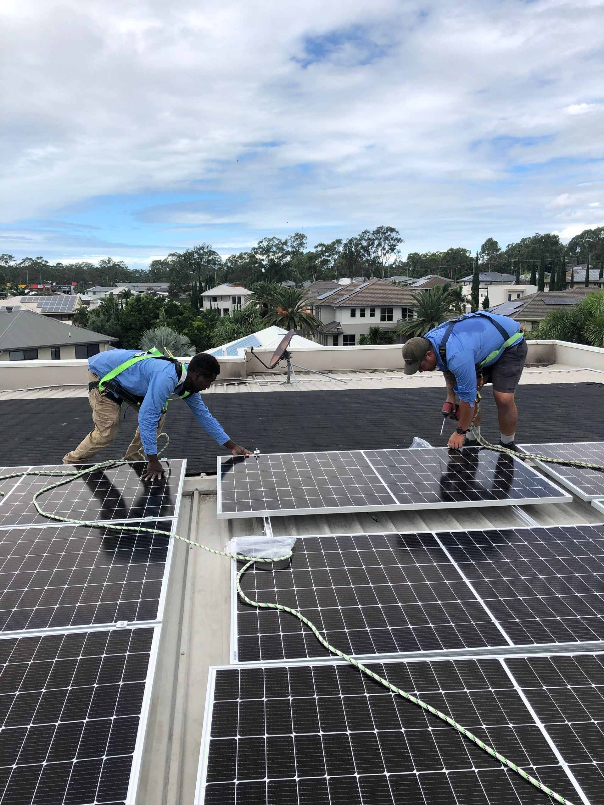 Hand pointing at a solar panel.  Blue solar cells against a light sky with other panels in the background.