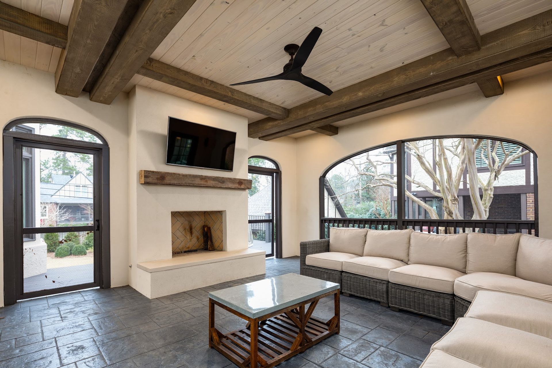 Covered patio with a fireplace, comfortable seating, and large windows.
