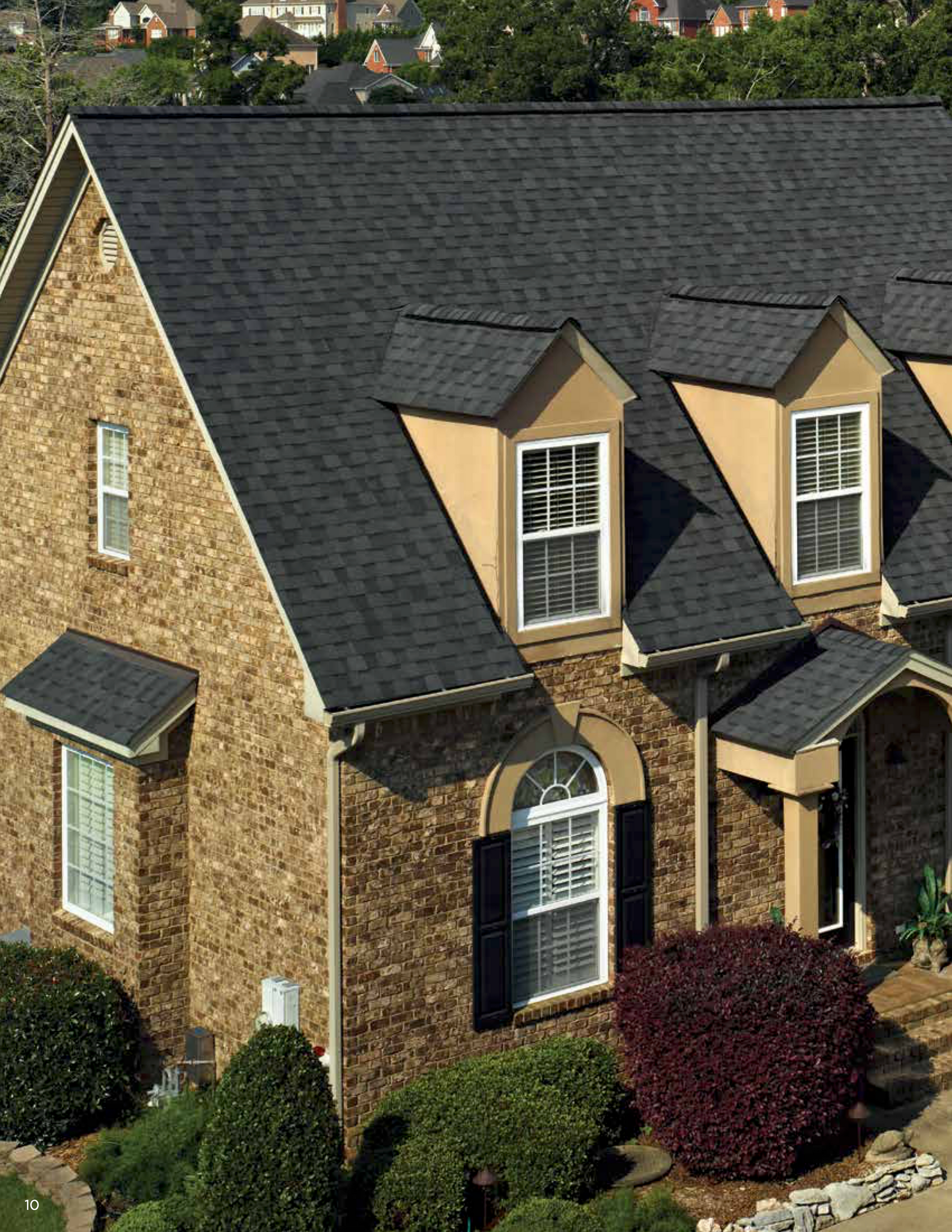 A brick house with a black roof and white windows