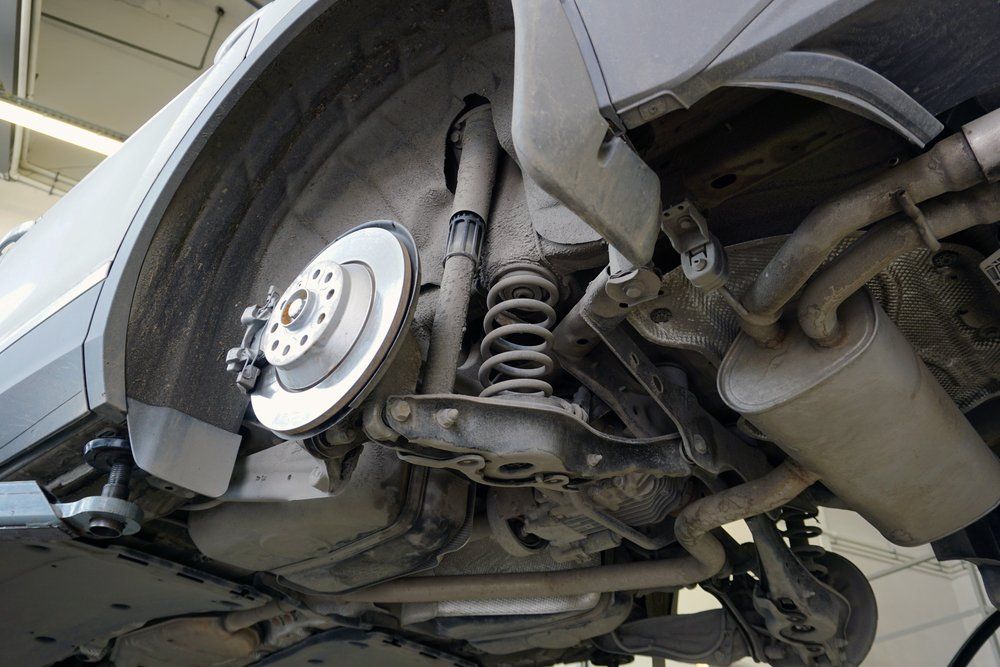 The underside of a car with a brake disc removed.