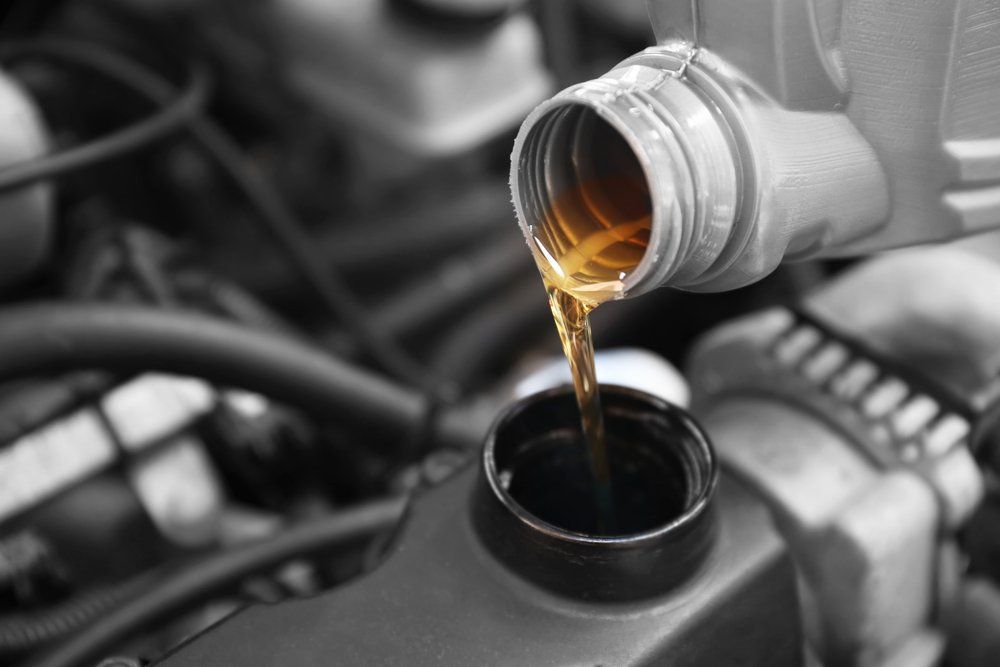 A bottle of oil is being poured into a car engine.