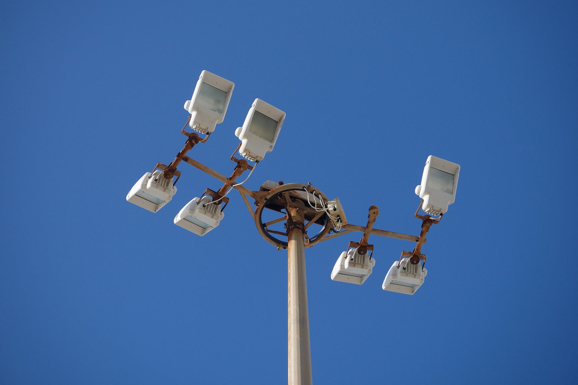 Light fixture on a tall pole against a clear, blue sky. It has six square lights.