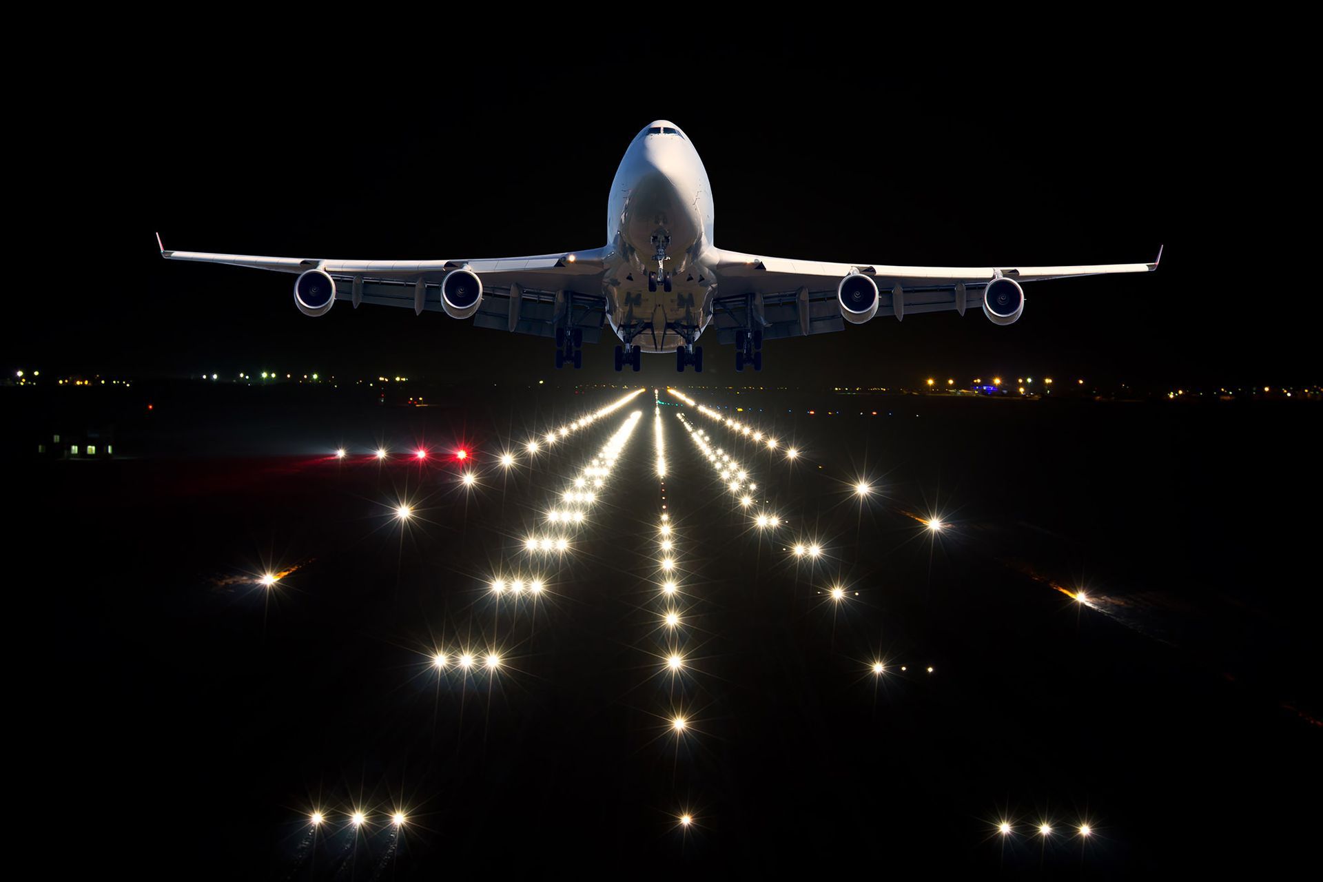 Airplane taking off at night, runway lights illuminate the scene.