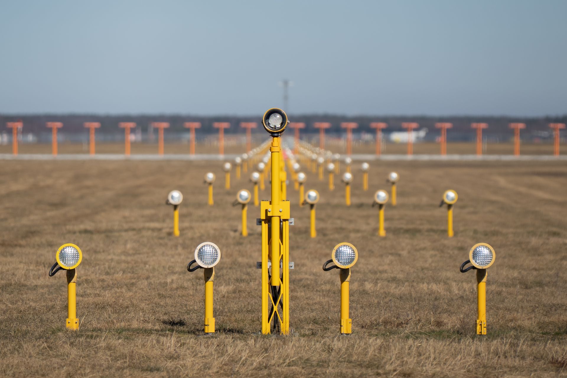 Runway approach lights in precise symmetrical alignment across an airport field.