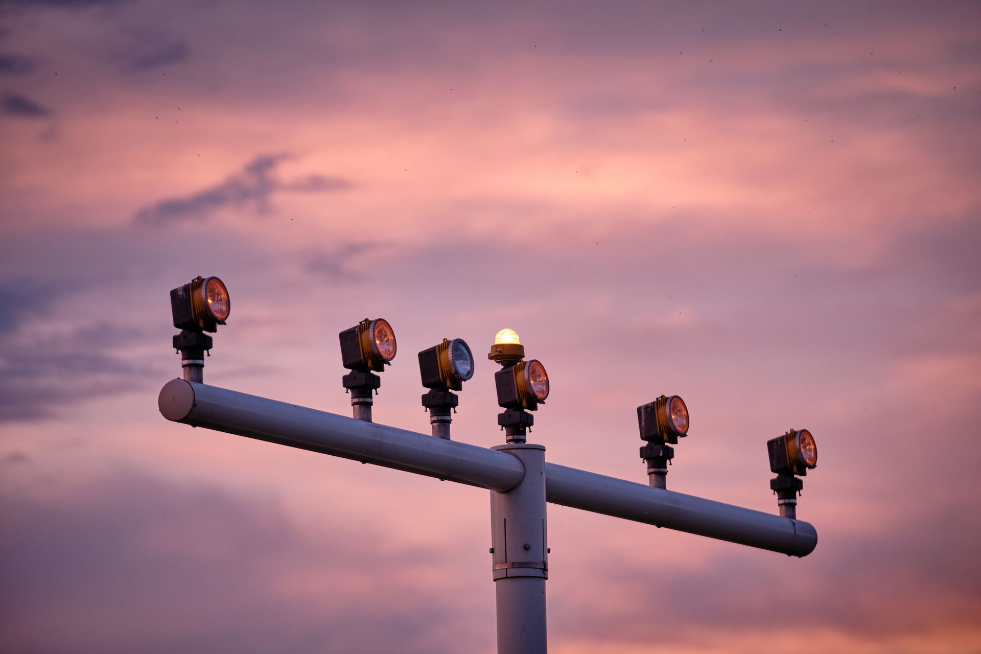 Airport approach lights against a sunset sky.