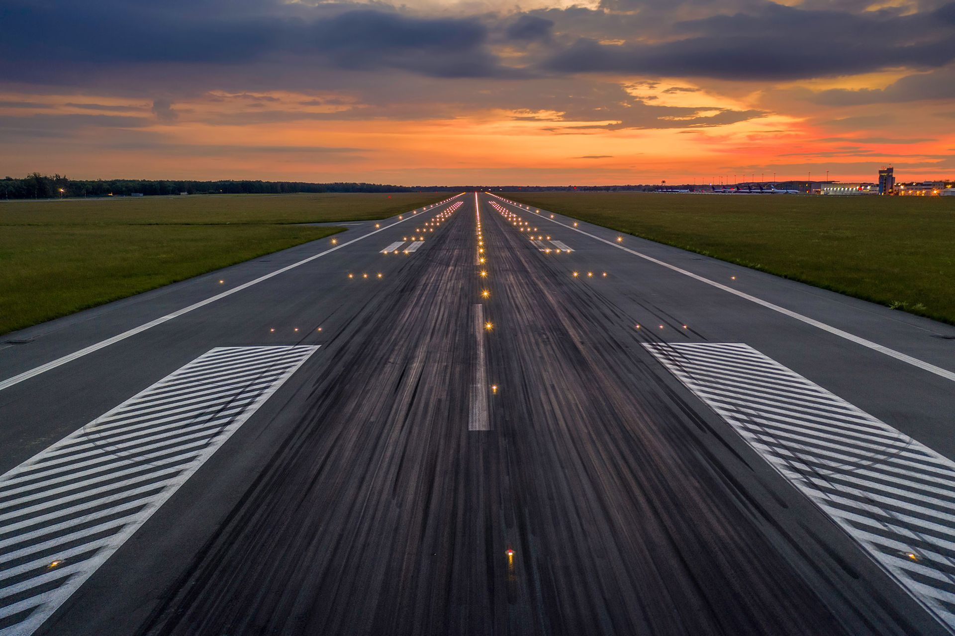 Airport runway at sunset with lights illuminated.