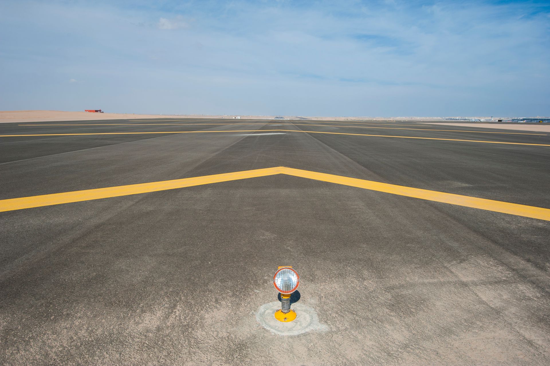 Airport runway with yellow markings and blue sky.