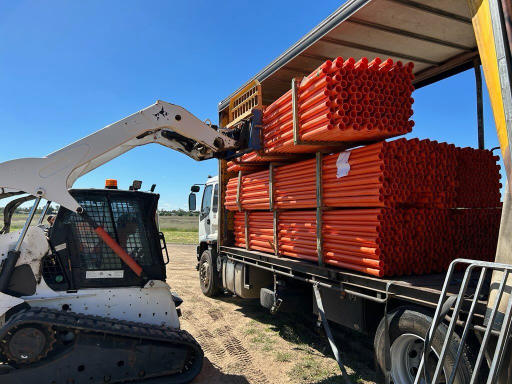 White airplane on a runway, facing forward. Blue sky backdrop.
