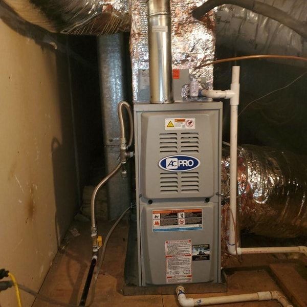 Furnace in a basement; gray unit with ducts and gas lines.