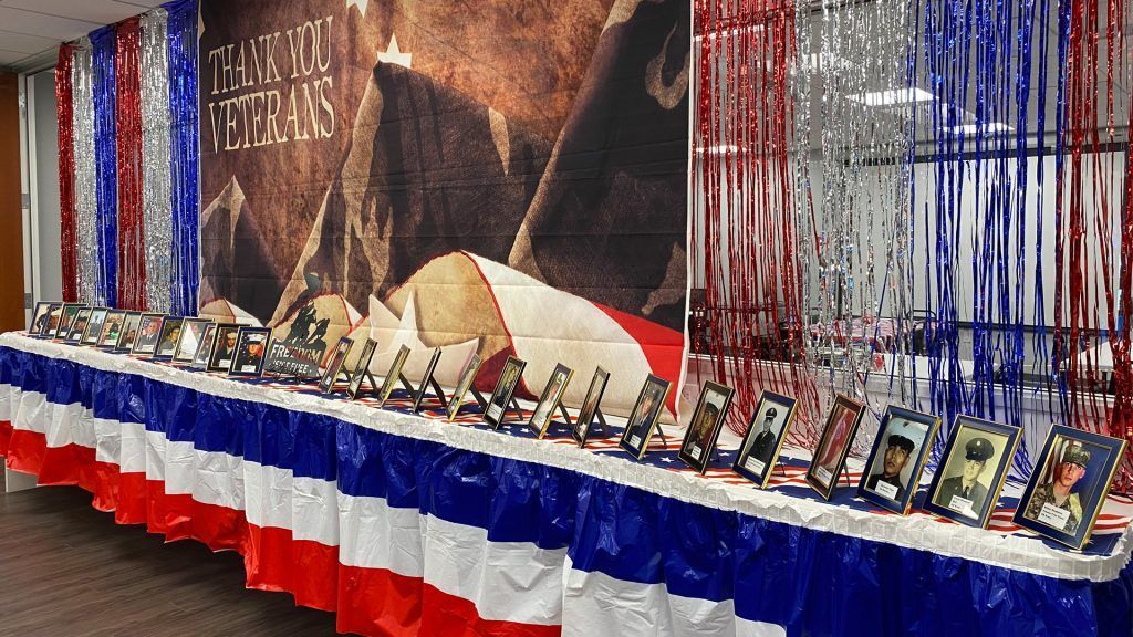 Display honoring veterans with photos, American flag colors, and a "Thank you Veterans" banner.