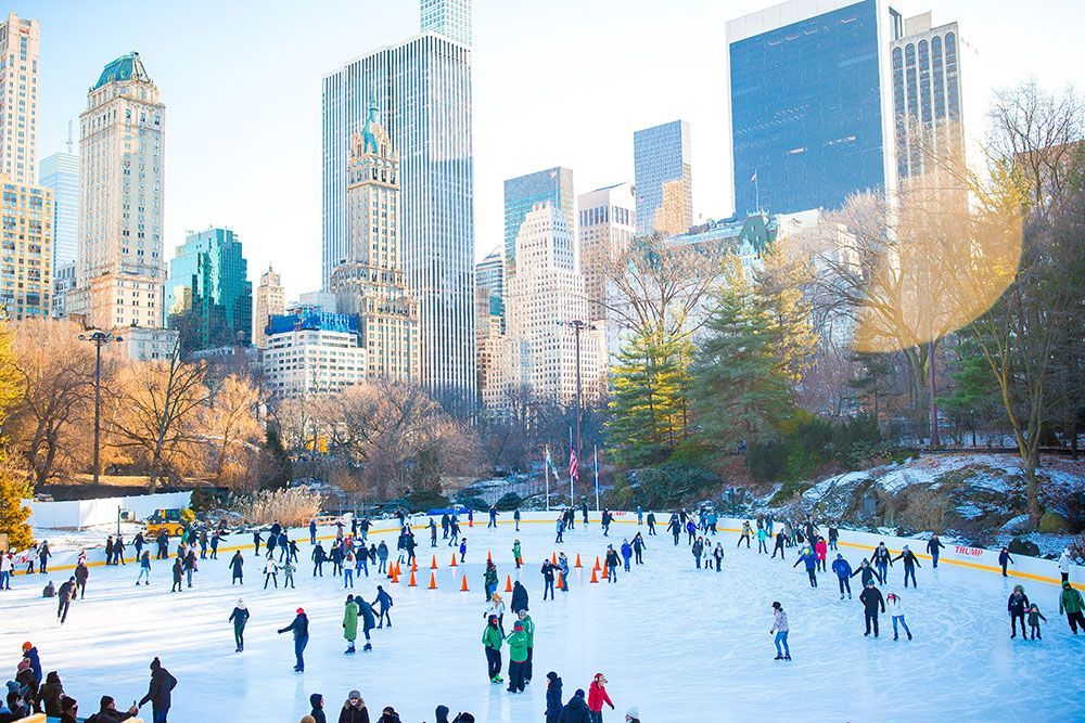 A group of people are ice skating in central park in New York City.