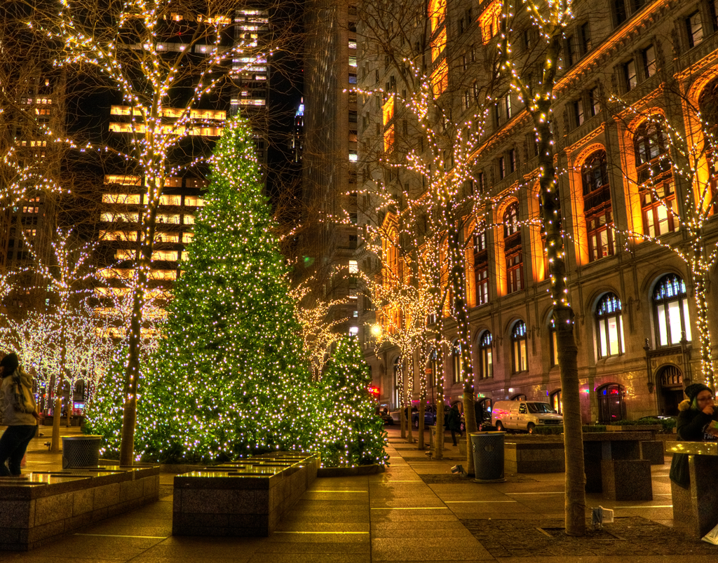 Christmas lights illuminate a city street with a large decorated tree.