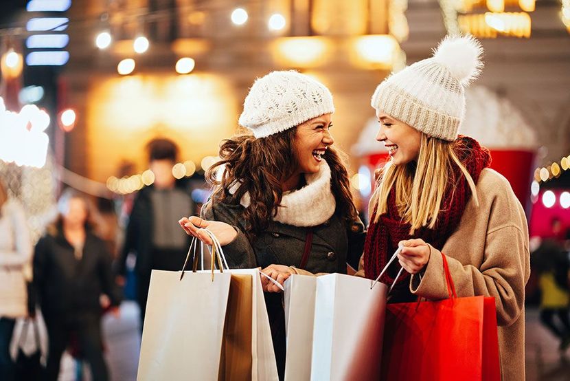 Two women are standing next to each other holding shopping bags