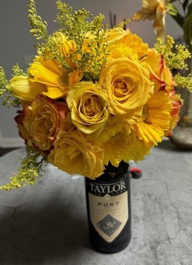 yellow flowers on top of a bottle of wine