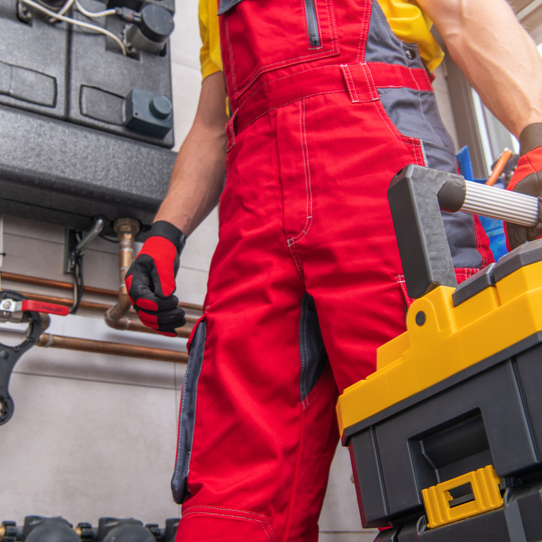 A man in red overalls is standing next to a yellow toolbox.