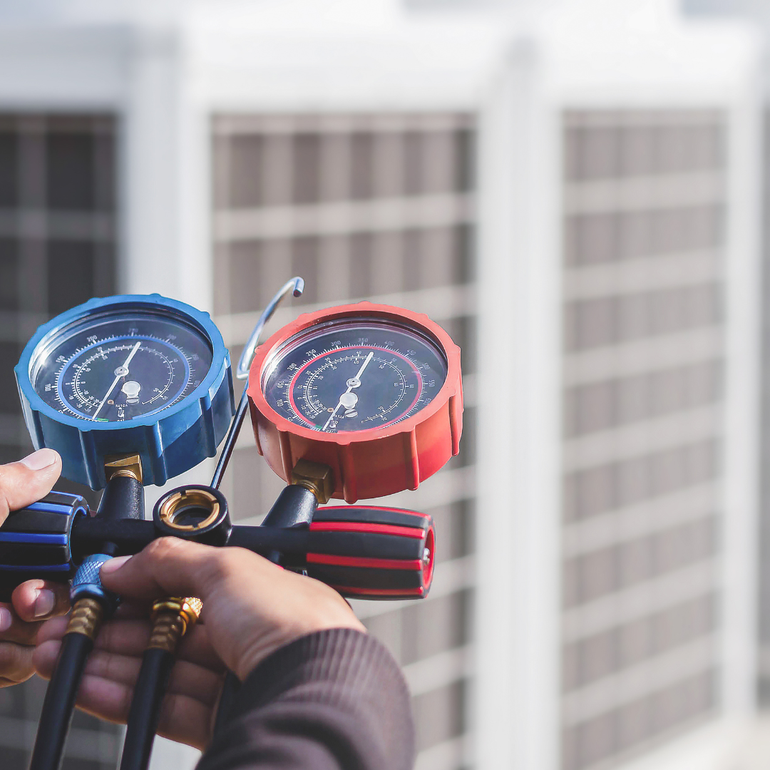 A person is holding a pressure gauge in their hand in front of a building.