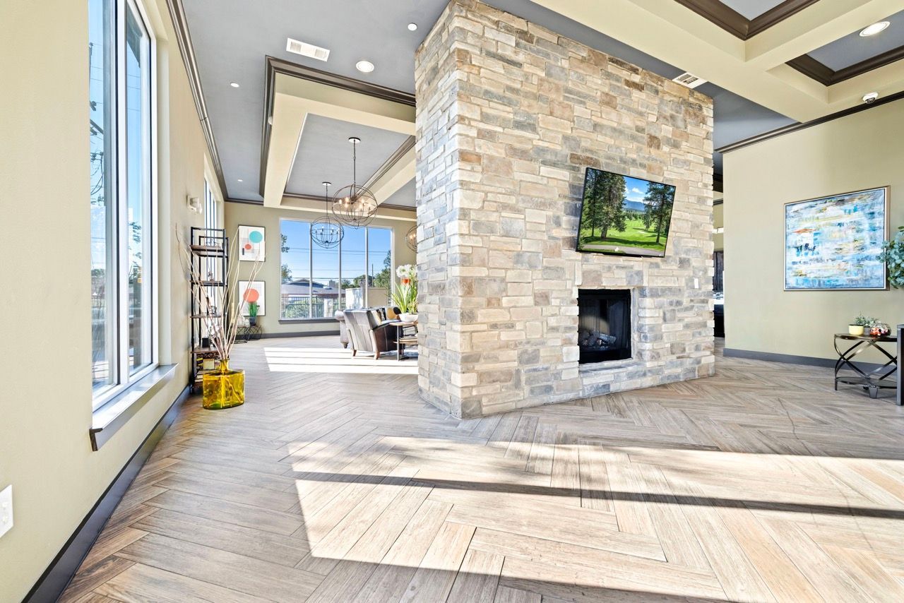 Bright lobby with a stone fireplace, mounted TV, and seating by large windows.