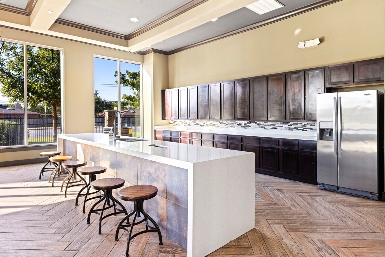 Modern communal kitchen with a large white island, dark wood cabinets, and bar seating.