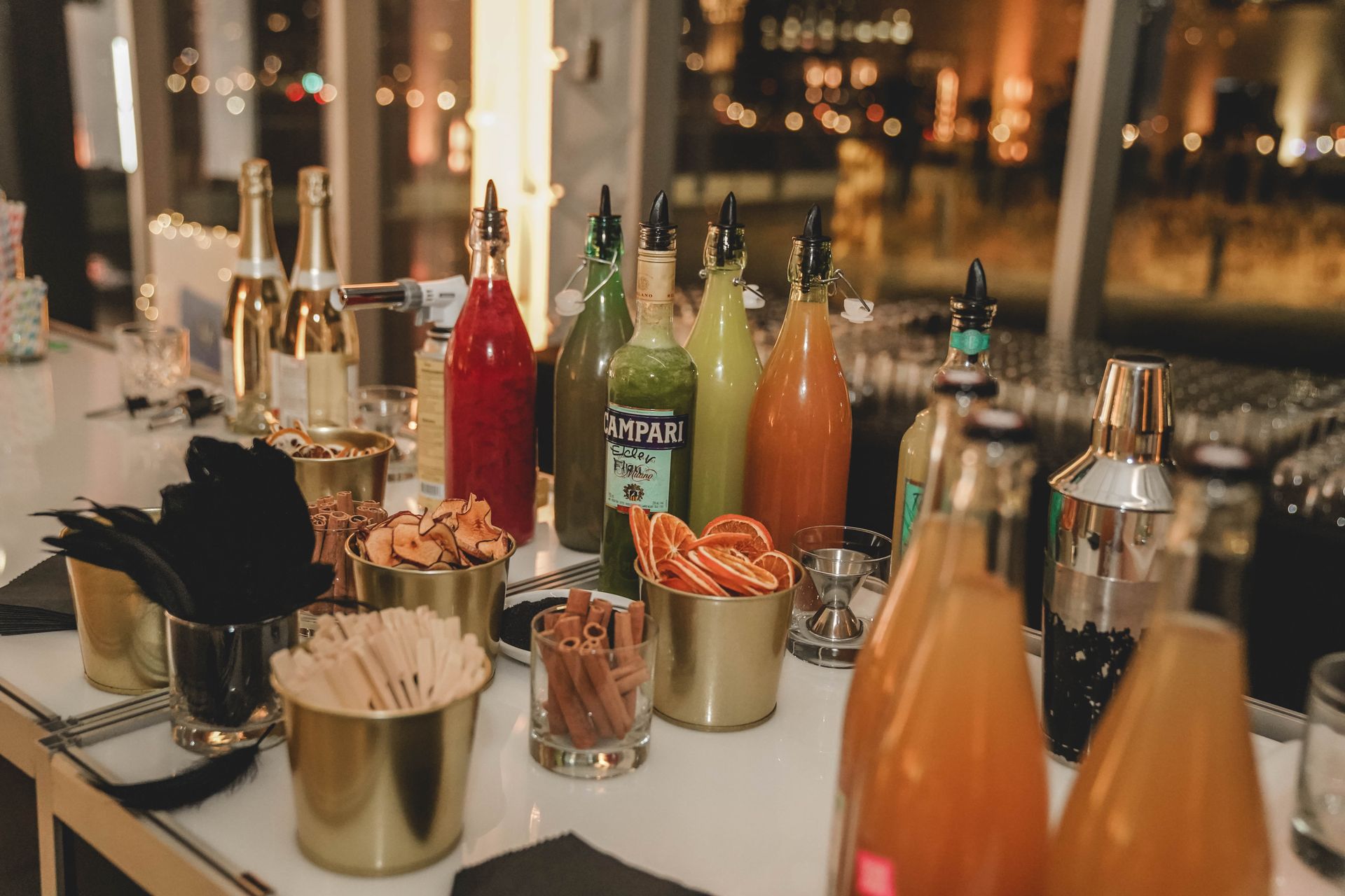 Bar proposant des bouteilles de jus, des mixers et des garnitures, avec une vue sur la silhouette de la ville en arrière-plan.