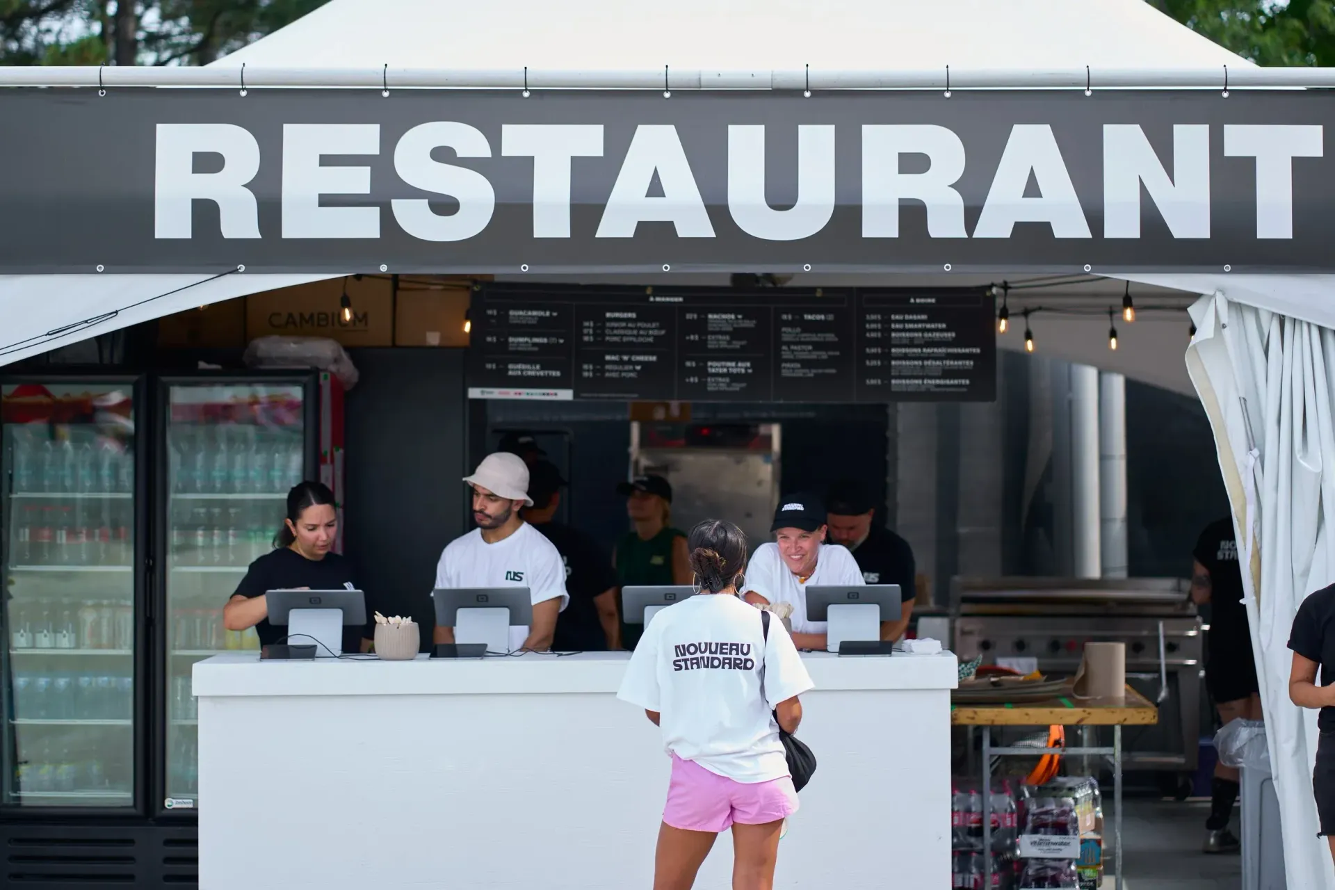 Restaurant avec personnel derrière le comptoir prenant les commandes ; un client se tient à proximité.