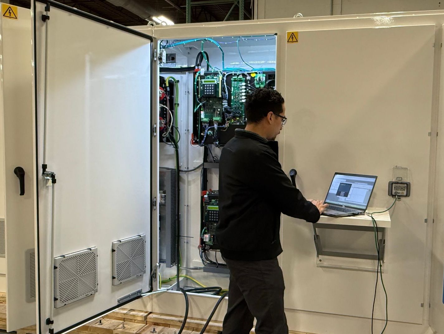 A man is working on a laptop in front of a large white box.