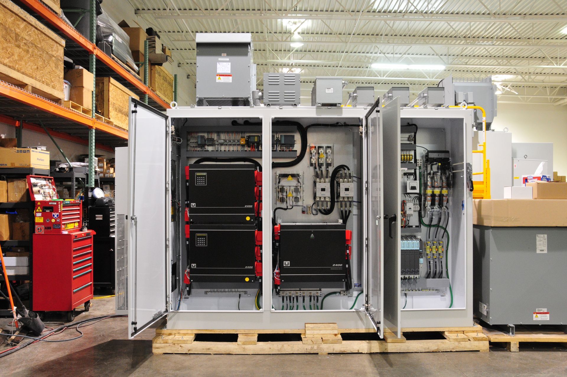 A large electrical box is sitting on a wooden pallet in a warehouse.