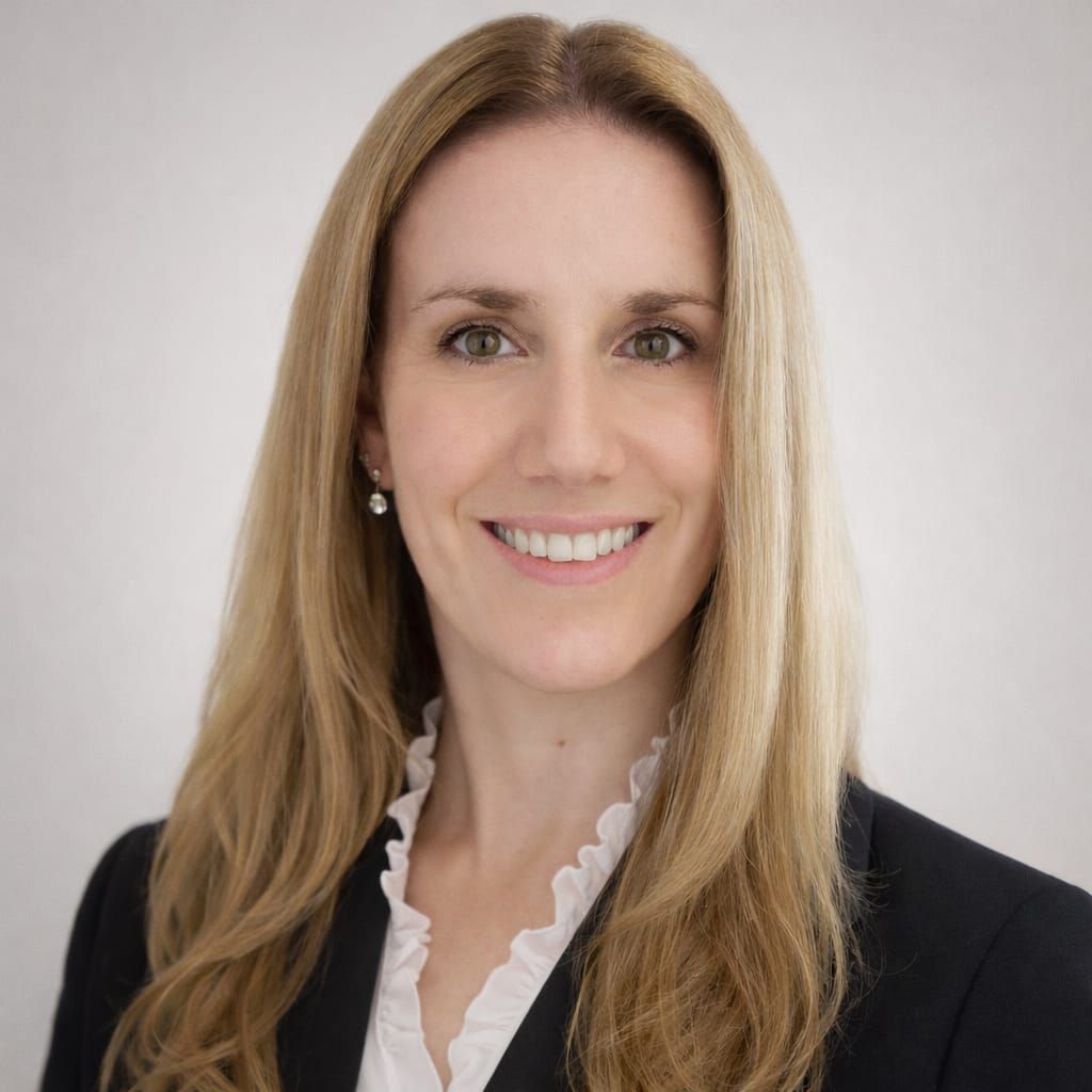 Una fotografía profesional de una persona con cabello largo y rubio, sonriendo, vistiendo un blazer oscuro sobre una blusa blanca con volantes.