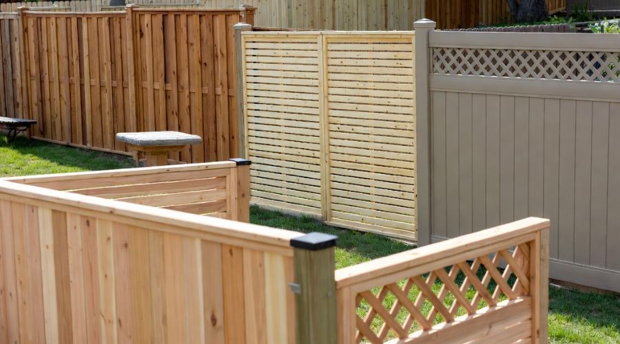 A backyard display featuring several styles of wooden and vinyl fencing, including lattice and privacy panels.