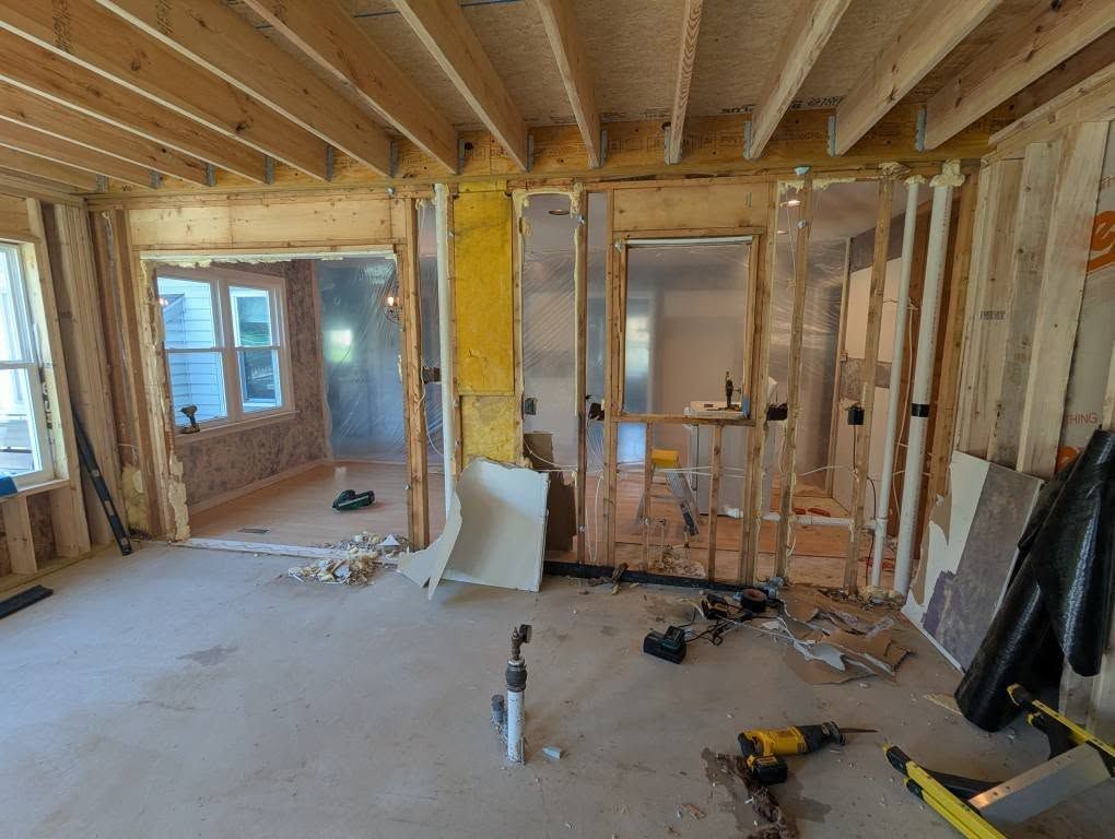 Interior of a room under construction with exposed wooden framing and insulation.