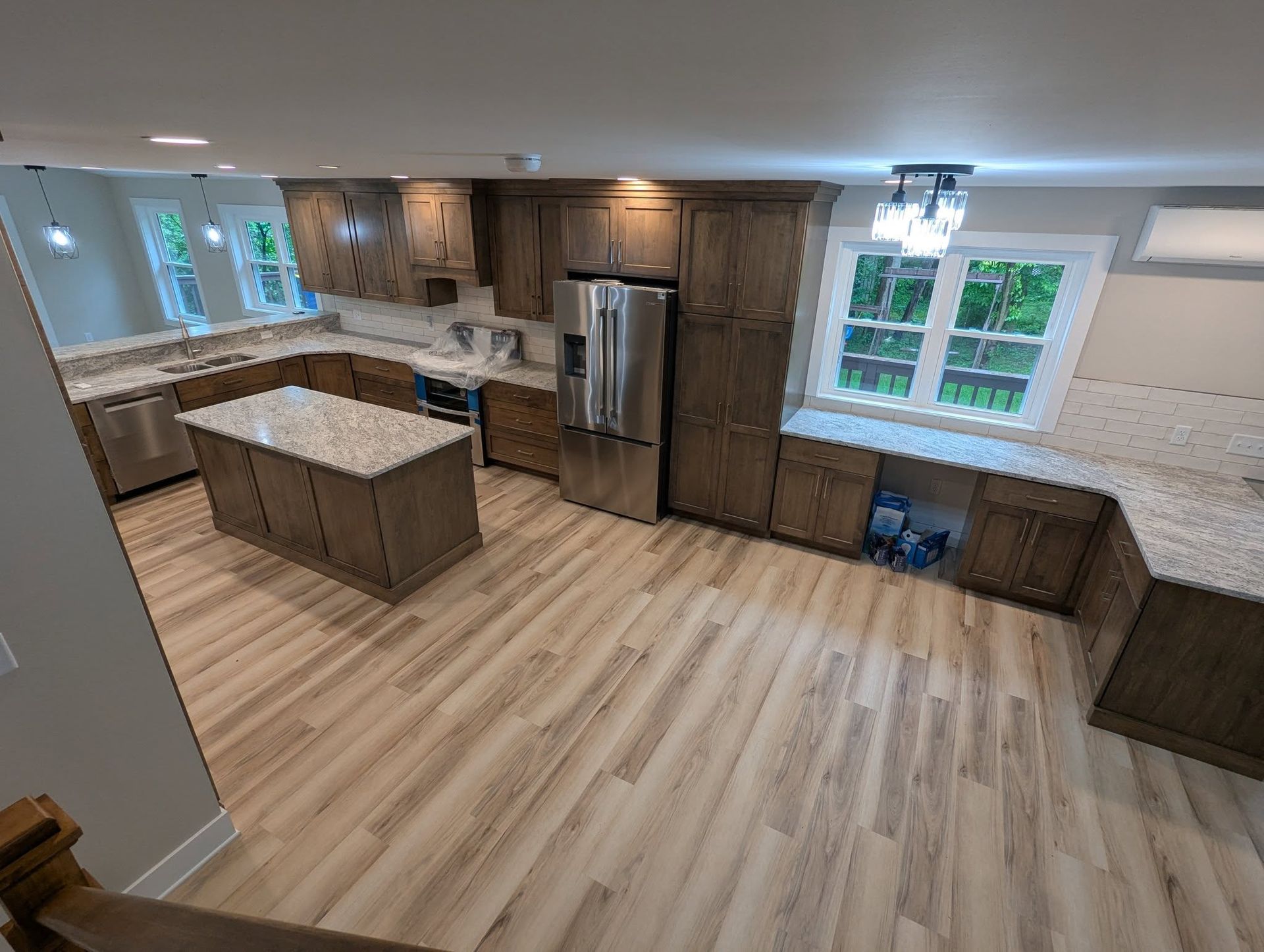 Spacious kitchen with wood cabinets, light countertops, stainless steel appliances, and wood-look flooring.