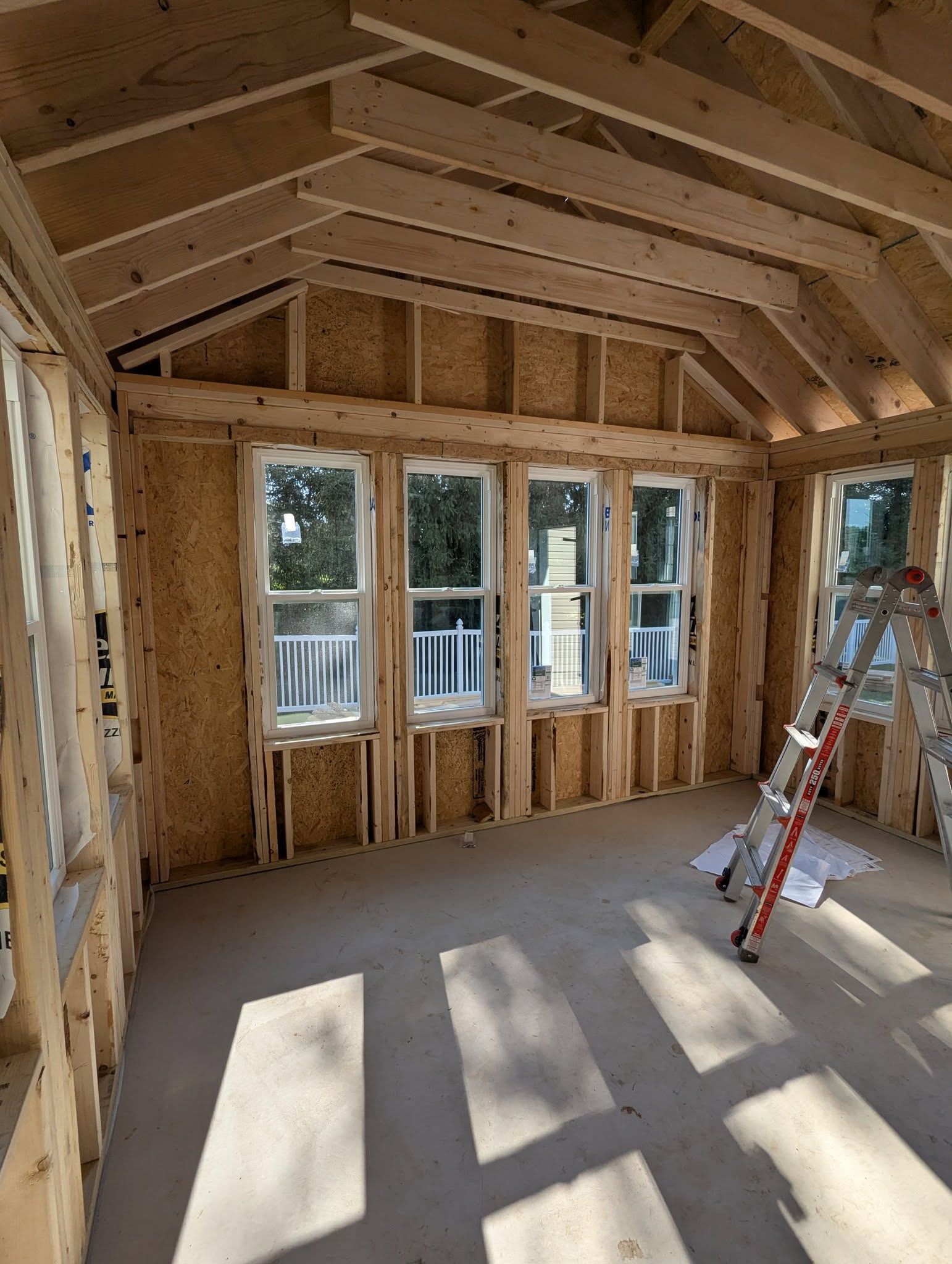 Woman in straw hat smiles, holding wine glass near a lake.
