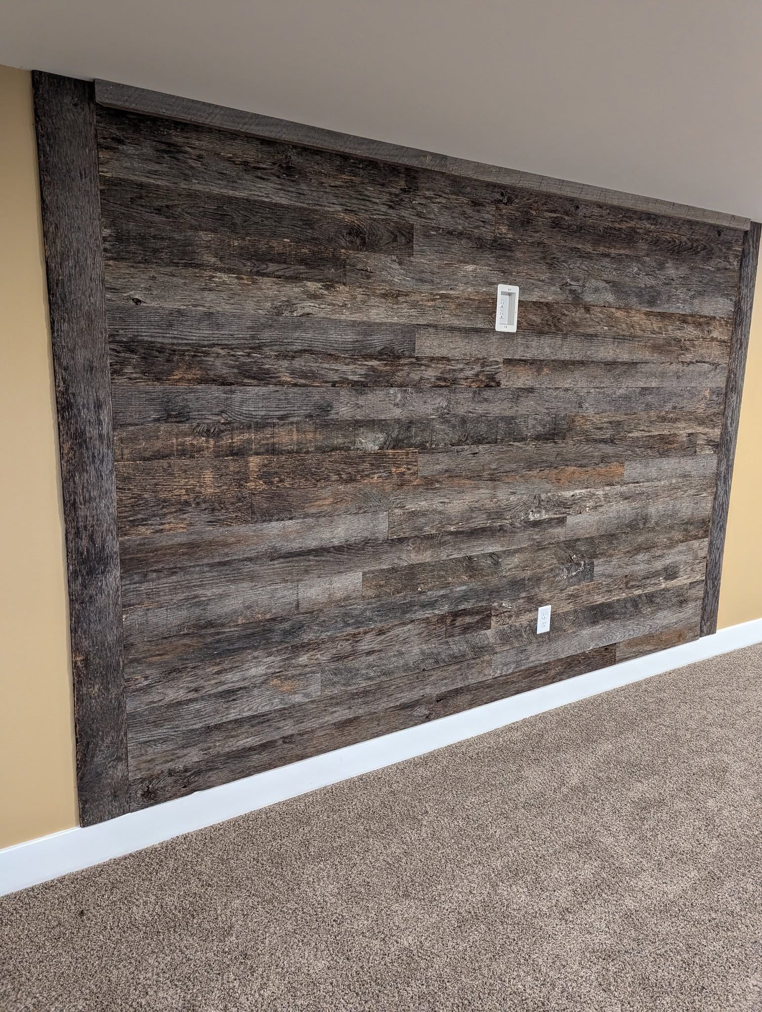 Wood plank wall with electrical outlets, beige and brown tones.