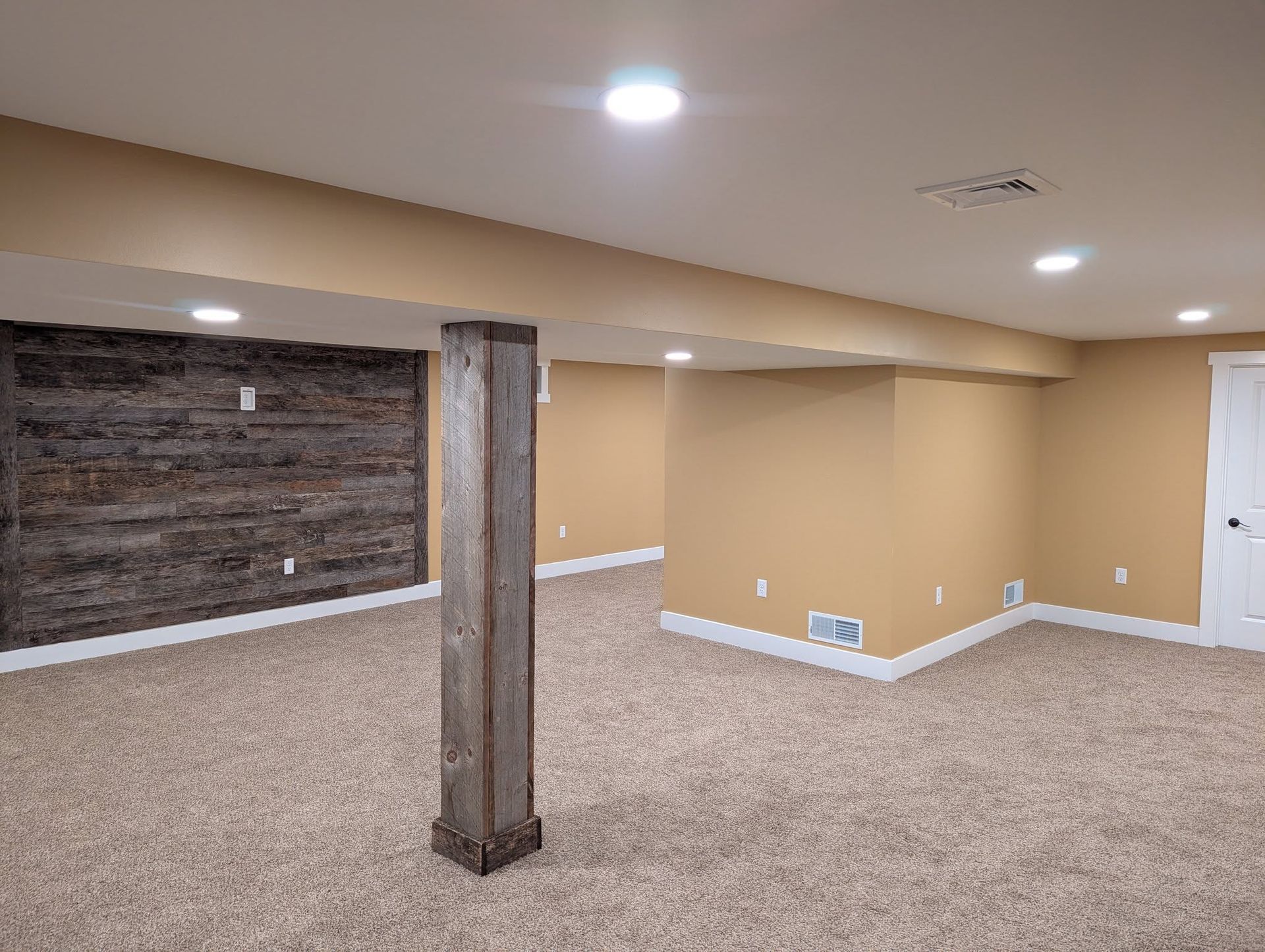 Woman in straw hat smiles, holding wine glass near a lake.