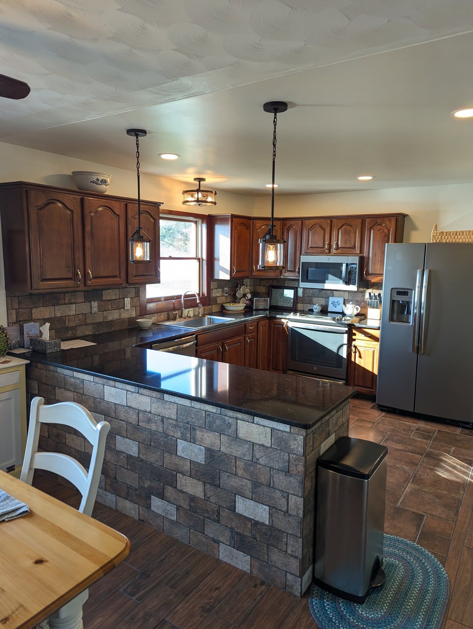 Kitchen with dark wood cabinets, a stone island, and stainless steel appliances.