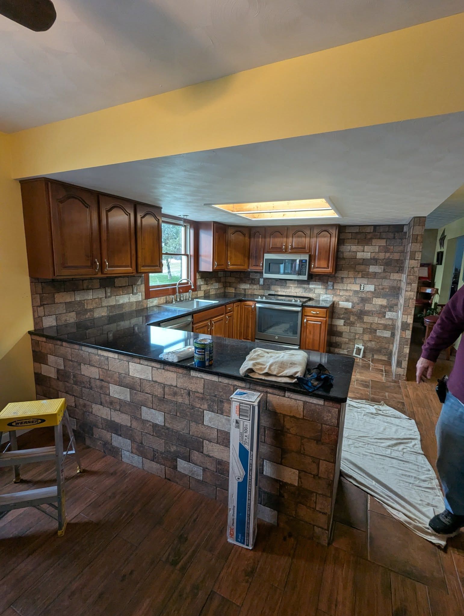 Woman in straw hat smiles, holding wine glass near a lake.