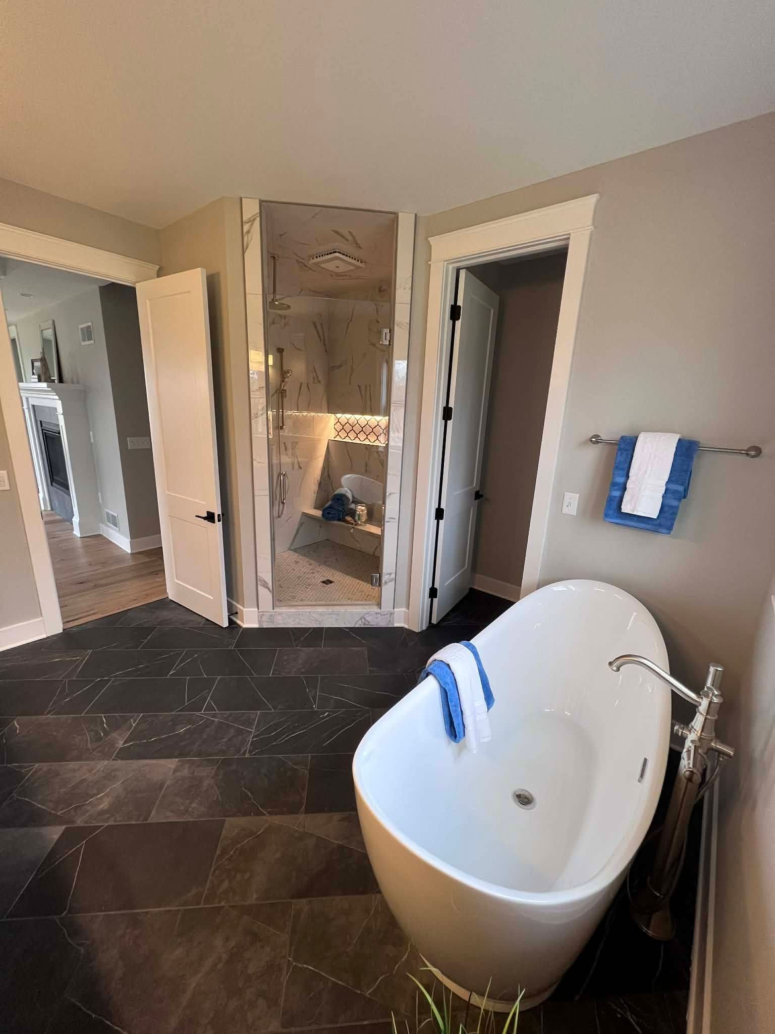 Woman in straw hat smiles, holding wine glass near a lake.