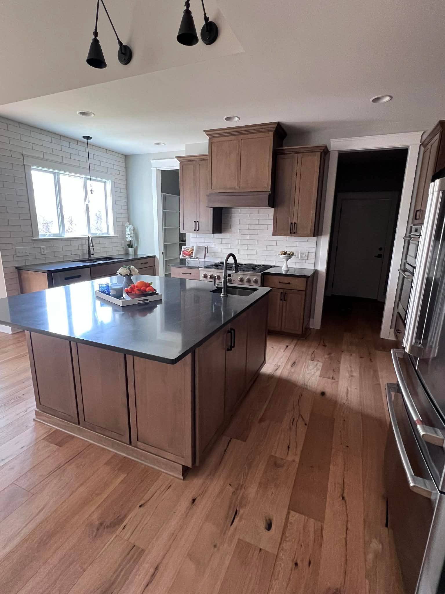 Spacious kitchen with wood cabinets, dark countertops, and large island with a cooktop.