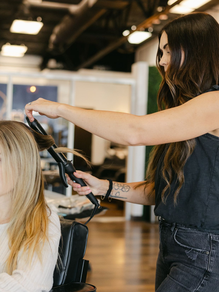 Hairdresser curling client's hair in a salon.