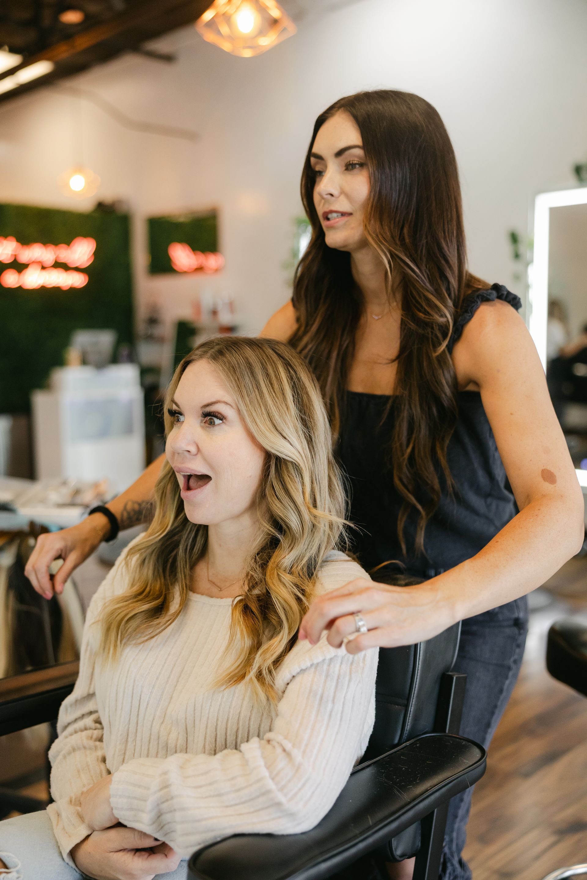 Woman in salon with stylist, reacting with surprise to her hair.