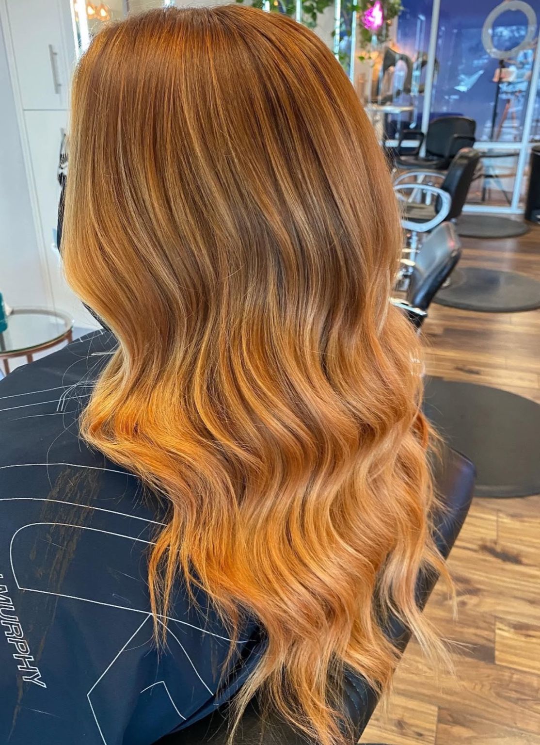 Woman with long, wavy, copper-colored hair styled at a salon.