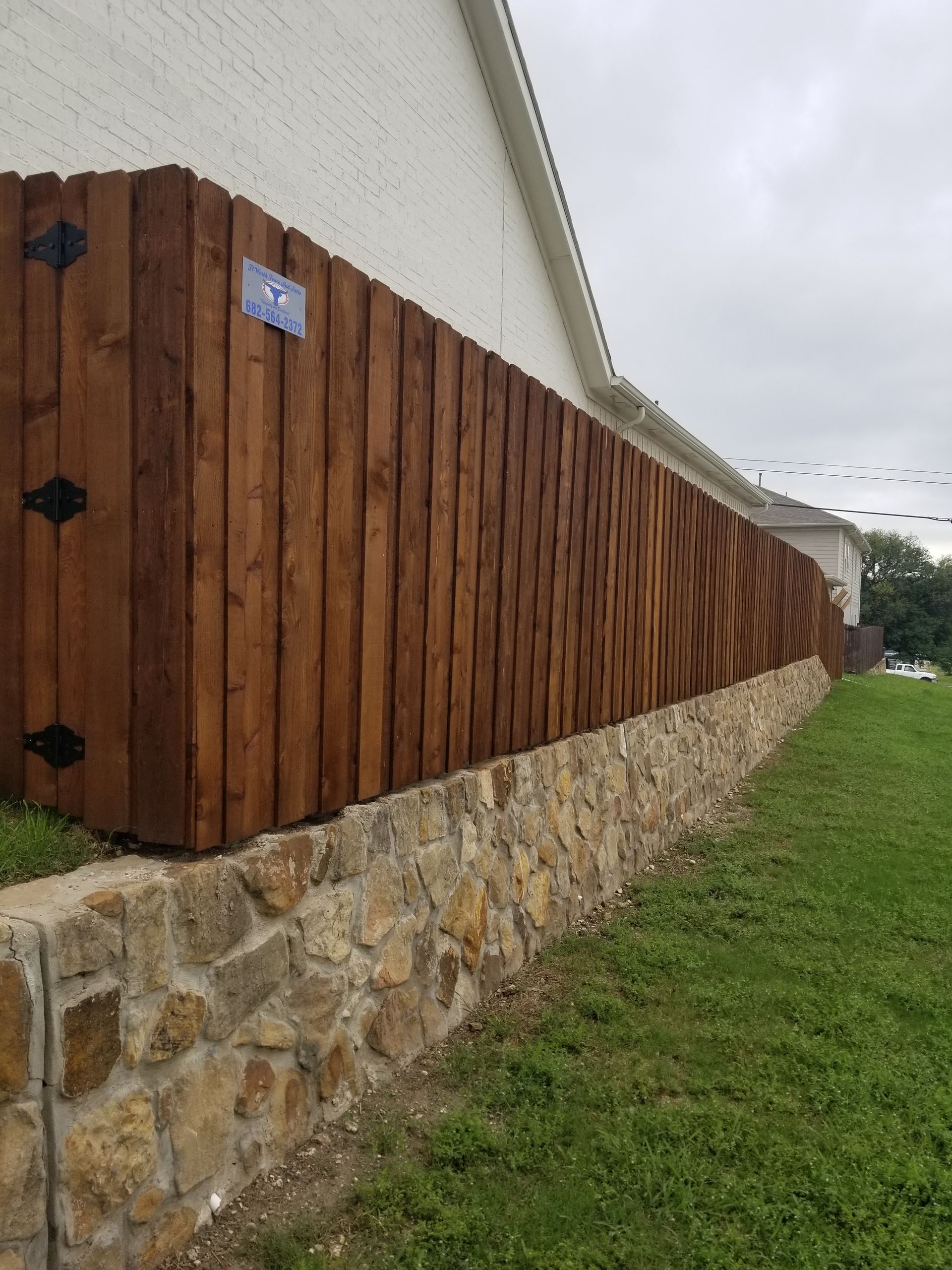Board on board wood privacy fence with a stone retaining wall