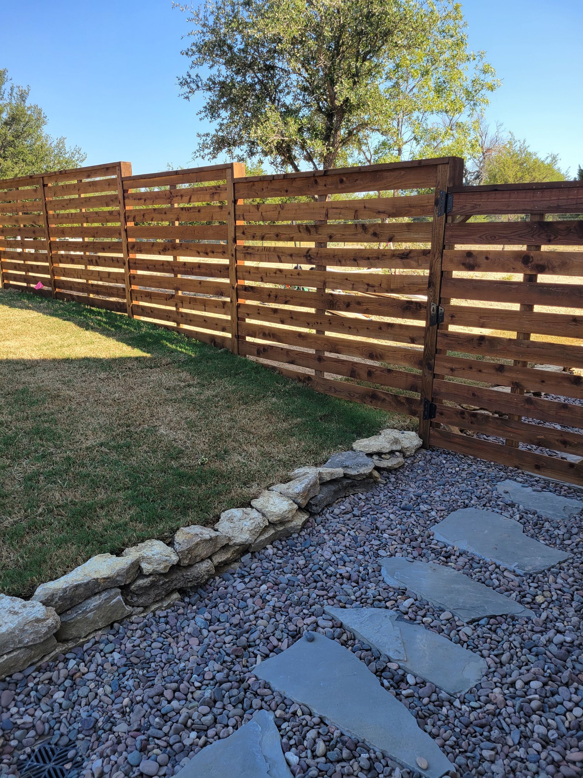 Modern style horizontal wood fence with natural stone walk path