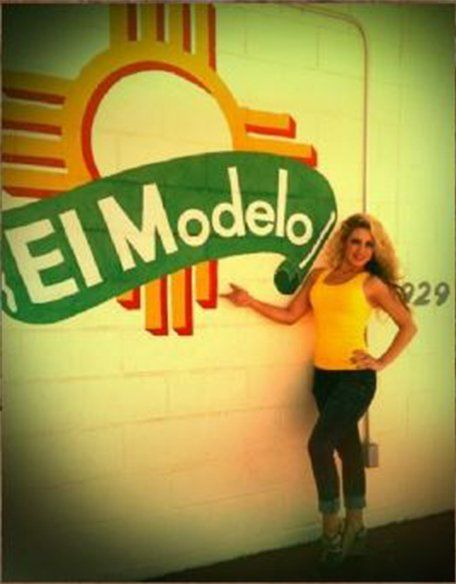 Mexican Foods — Woman Standing Right Beside The El Modelo's Sign in Albuquerque, NM
